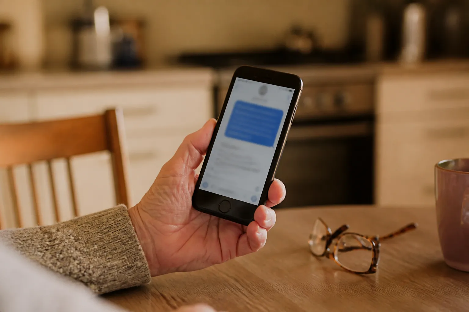 A phone in hand showing a text with a link